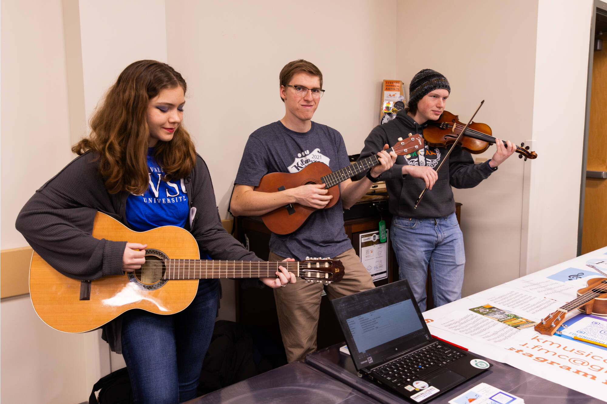3 students from folk music club playing various string instruments